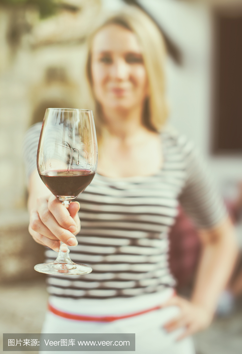 一個女人在室外遞上一杯紅酒。復古的效果。